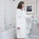 A woman pulling down a white PT Rail next to a toilet.