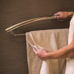 Invisia Towel Bar, with a towel hanging and a person holding the rail
