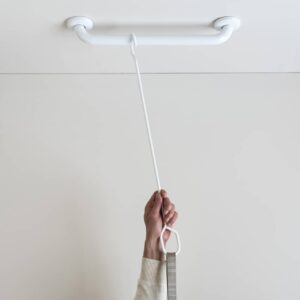 Photo showing how HealthCraft's e2 Ceiling Mount Trapeze is mounted to the ceiling with a small white grab bar with a hand hanging the trapeze's hook mechanism from the ceiling-mounted bar. 