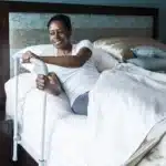 A woman leans on the HealthCraft Smart Rail to pull herself up to sit in bed.