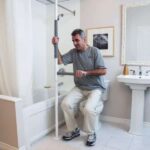 Man standing up from the toilet, using the SuperPole with SuperBar for support