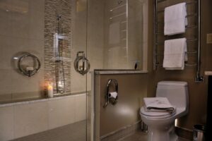 a candle lit bathroom with multiple safety products in sight, including; a soap dish and a toilet paper holder.