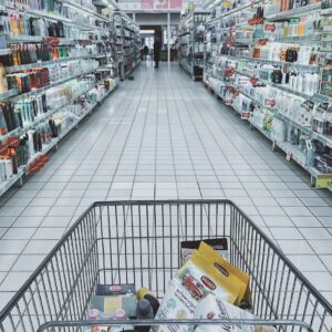 Photo of a shopping cart moving down the aisle of a retail store.