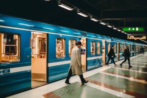 Photo of a subway train stopped with its sliding doors open, and people exiting the train.