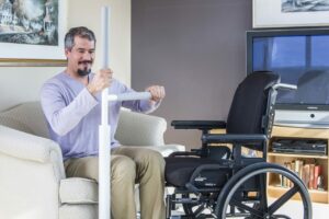 Man using a SuperPole to move himself from a seat to his wheelchair