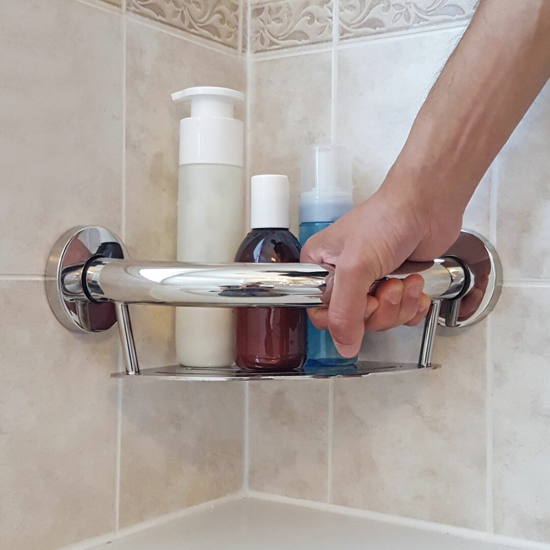 Plus Series Corner Shelf in a tiled bathroom with a hand holding it for support