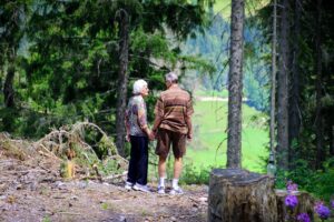 older adult couple holding hands on a walk through the forest