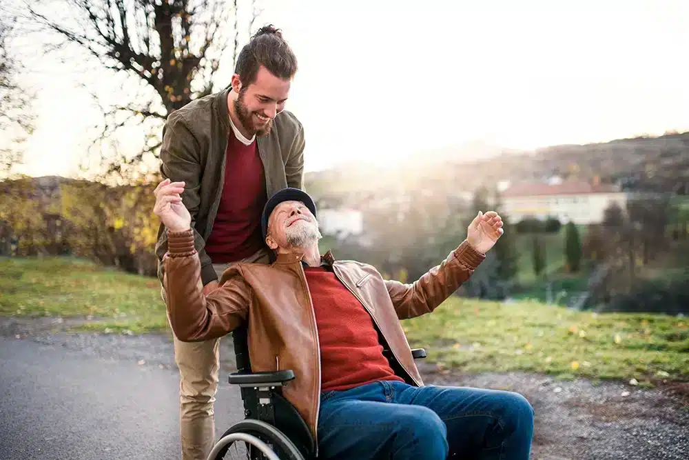 Son pushing father in wheelchair looking happy