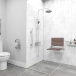 A safe bathroom, with multiple support bars and transfer seat in a polished chrome finish