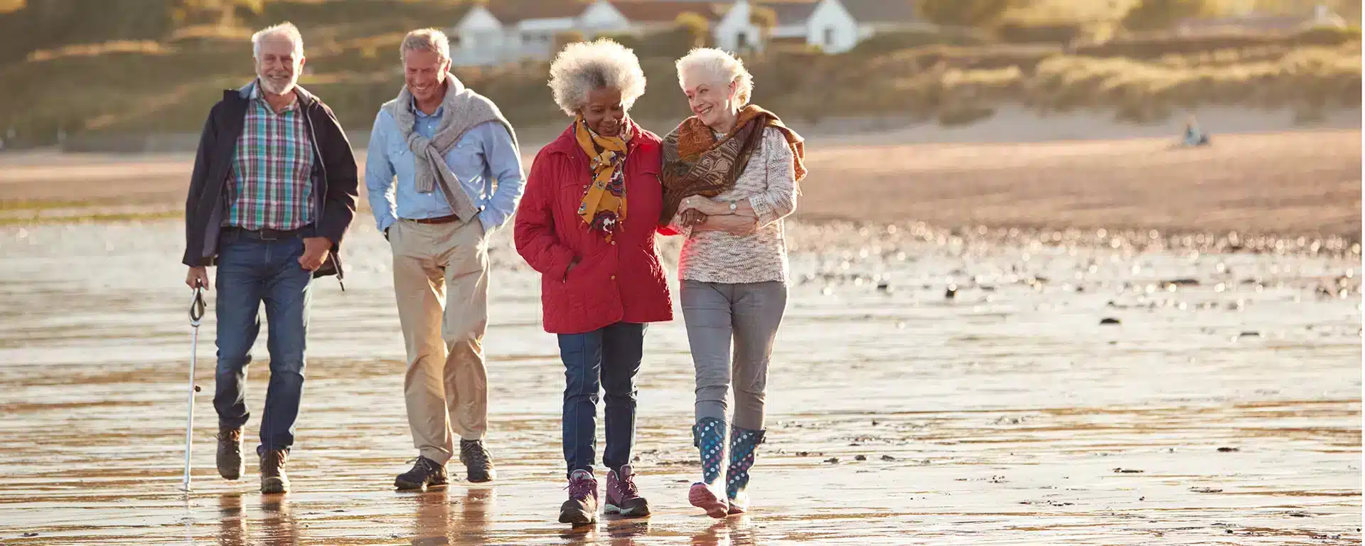A group of seniors walking together on the beach on a windy day.